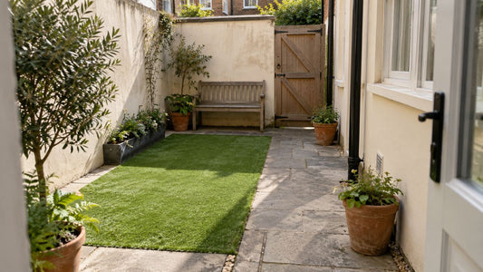 Artificial grass lawn bordered by paving, climbing plants and a bistro seating area in a brick courtyard.